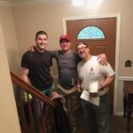 Three friends posing on a staircase, smiling warmly.