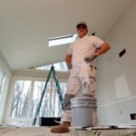 Man standing on a bucket in a room under renovation.